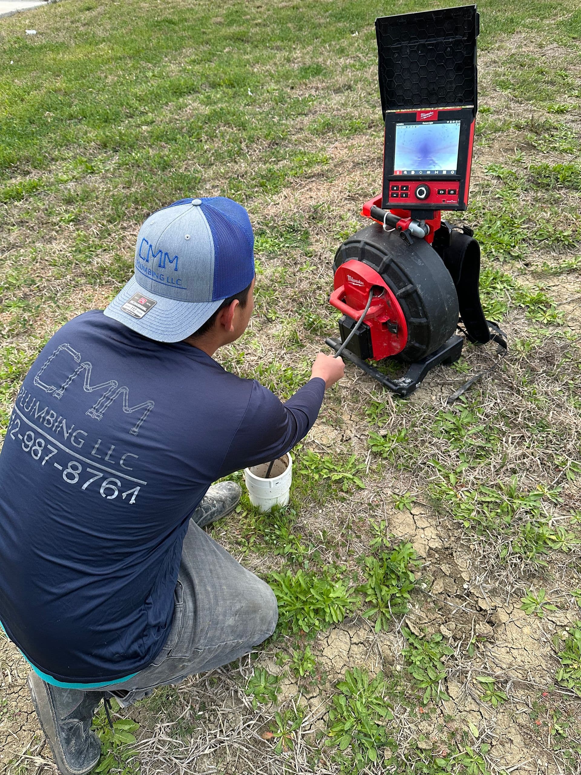 CMM Plumbing technician performing a drain camera inspection outdoors