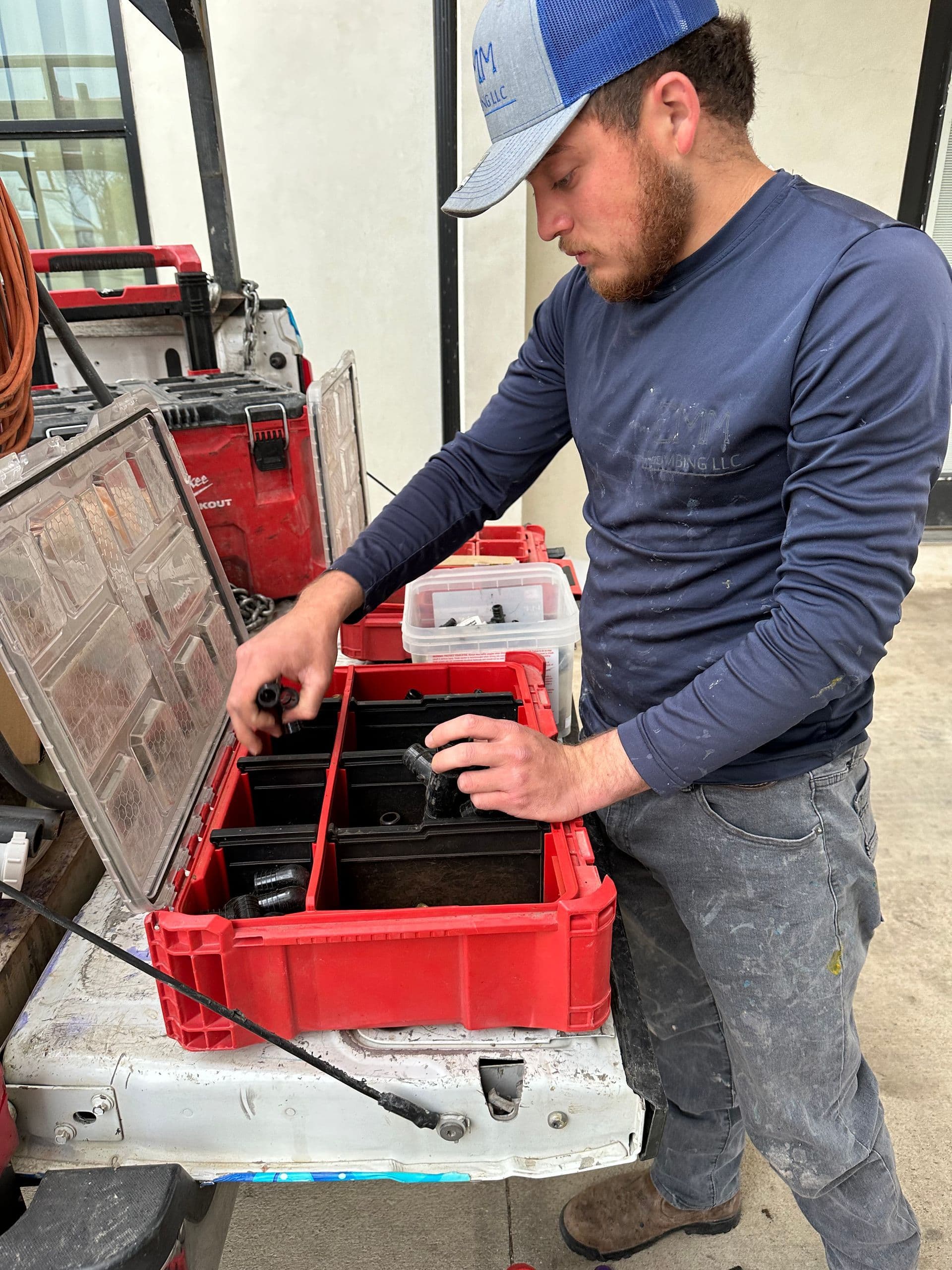 CMM Plumbing technician organizing parts and fittings on a job site