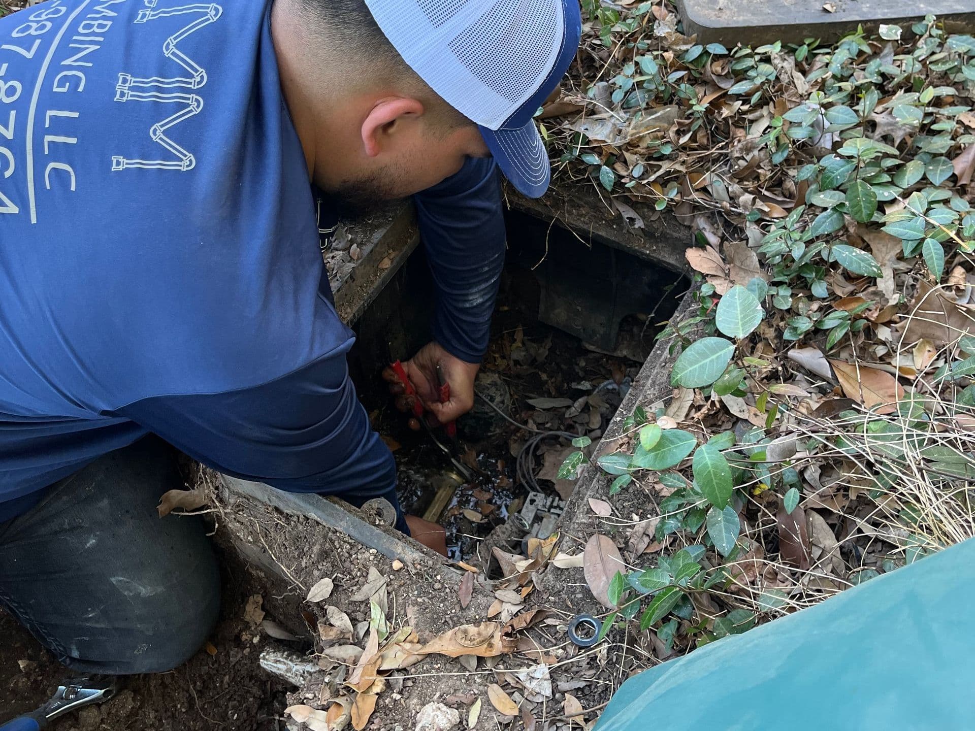 A CMM Plumbing technician inspecting a commercial backflow prevention assembly inside an outdoor utility box