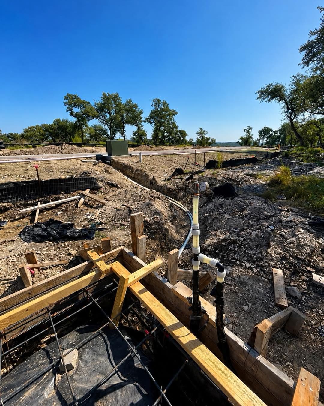 A trench at the slab edge where the water and gas lines enter the building, stubbed up and ready for inspection.